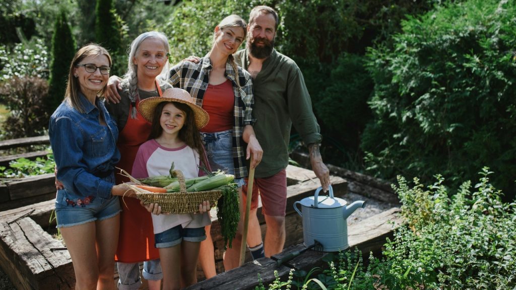 happy-farmer-family-looking-at-camera-and-holding-their-harvest-outdoors-in-garden