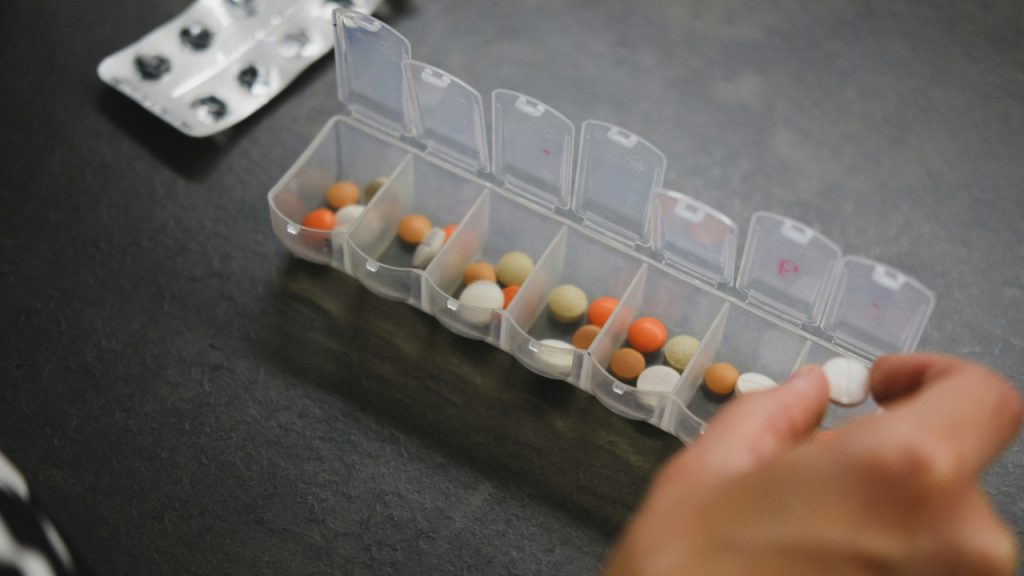 person-about-to-pick-medicine-from-medicine-organizer-1TL8AoEDj_c