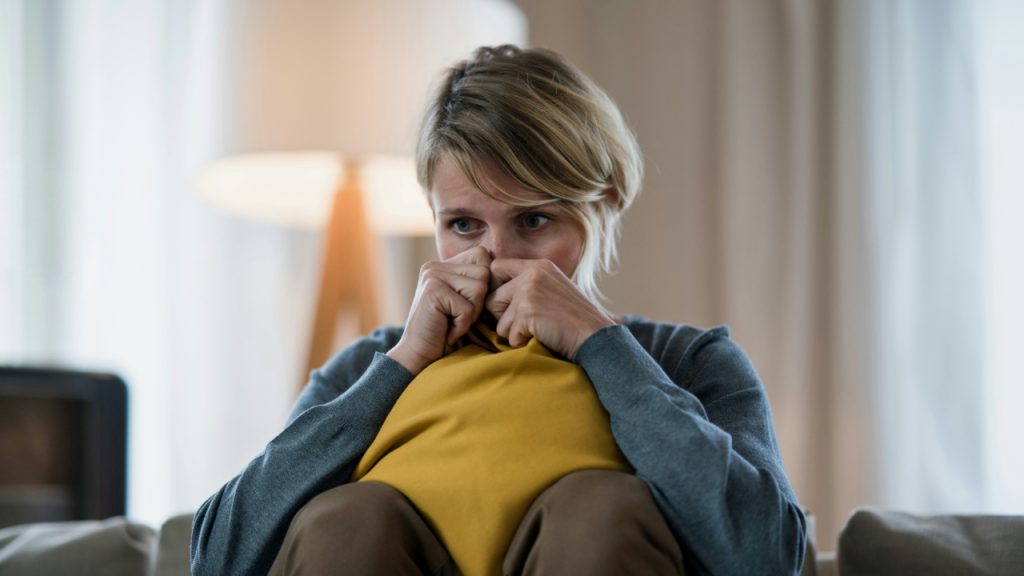 worried-woman-with-tablet-indoors-on-sofa-at-home-feeling-stressed-mental-health-concept
